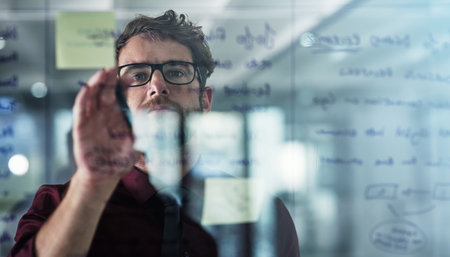 First, define the problem. a young businessman brainstorming with sticky notes on a glass wall in a...