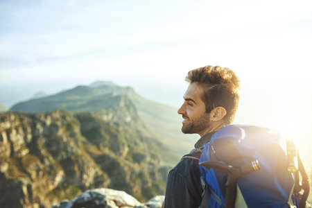 Dare to experience life. a young man hiking up a mountain.の写真素材