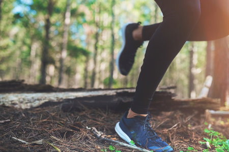 Be proud of every step you take. an unrecognizable young woman out for a jog in the woods.の写真素材