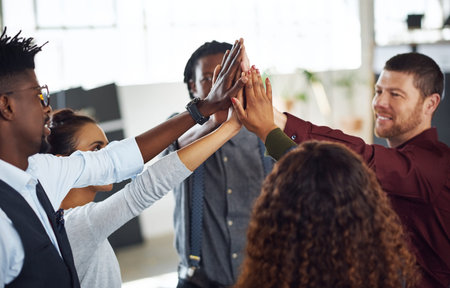 Success will be ours as a team. a group of businesspeople high fiving together in an office.