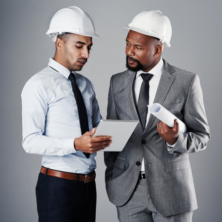 How can we improve this design. two civil engineers discussing building plans while standing in the studio.の写真素材