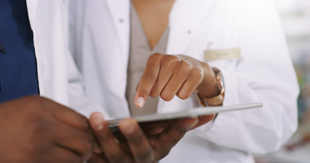 Letss use this one right here. Closeup shot of two unrecognizable healthcare professionals using a digital tablet while having a discussion.の写真素材