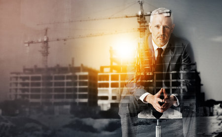 Building my empire from the ground up. Portrait of a handsome mature businessman superimposed over a construction site.の写真素材