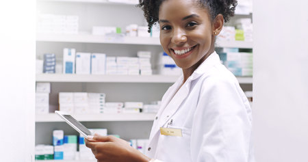 Avoid long queues by using our app. Cropped portrait of an attractive young pharmacist holding a digital tablet in a chemist.の写真素材