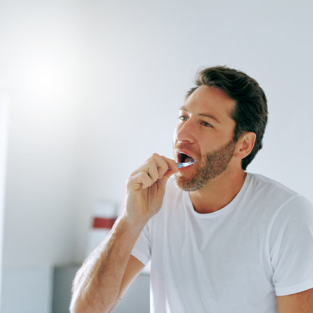 Fresh breath, fresh day. a handsome middle aged man brushing his teeth in the bathroom at home.の写真素材