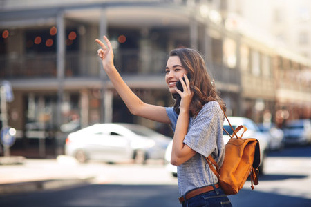Looks like my rides here...an attractive young woman making a phonecall while hailing a taxi out in the city.の写真素材