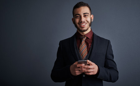 Im easy to reach. Studio portrait of a stylish young businessman sending a text message while...