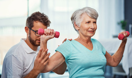 Keeping up her strength. a senior woman working through her recovery with a male physiotherapist.の写真素材