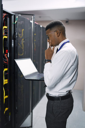 This problem is looking tricky. a young male technician working in a server room.