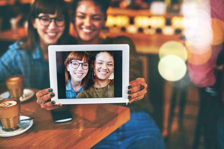 Besties always take plenty of selfies. two young friends taking a selfie together in a cafe.の写真素材