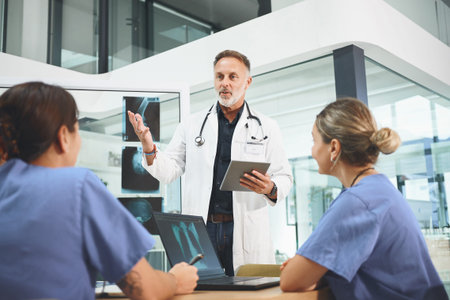Managing his department with regards to patient care. a mature doctor leading a discussion with his...