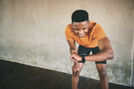 Dont count the miles, make the miles count. a man looking at his watch during a workout against an urban background.の写真素材