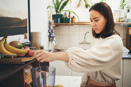 This smoothie is going to be delicious. a young woman using her blender to make a smoothie.の写真素材