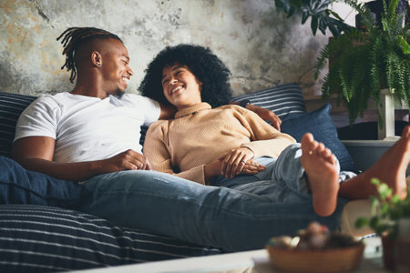 Being in love with you makes every day an interesting one. a young couple relaxing together on a sofa at home.の写真素材