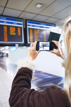 This ones for the photo album. a woman taking a photo of the time for her flight at the airport.