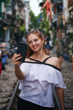 I keep selfies of every city I visit. a young woman taking selfies while exploring a foreign city.の写真素材