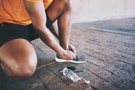 Get your foot into the fitness game. a man tying his shoelaces during a workout against an urban...