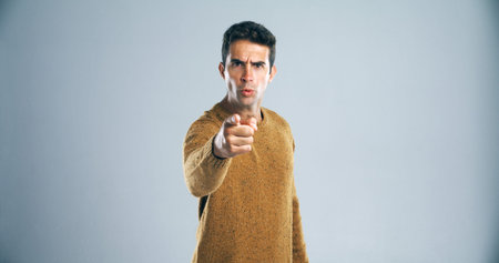 Dont make me say it again. Studio shot of a handsome young man pointing a finger in anger against a...