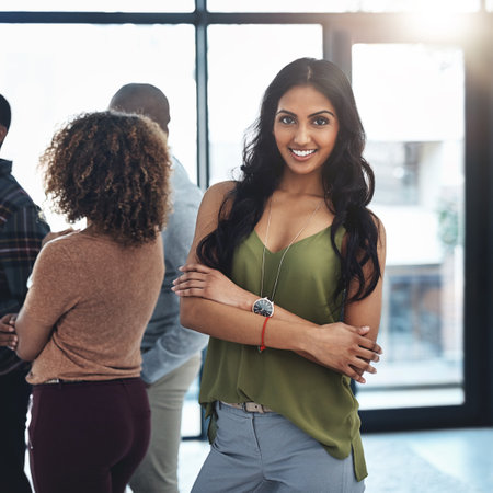 Ive got just the team for the job. Portrait of an attractive young woman standing in the office with her colleagues in the background.の写真素材