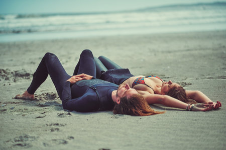 That after after surf nap. a young couple relaxing after a surf at the beach.の写真素材