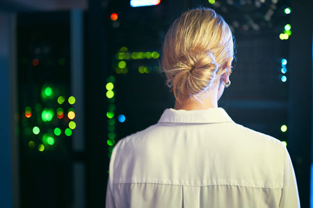 Listening to the hum from the machines. an unrecognizable IT specialist standing alone in the server...