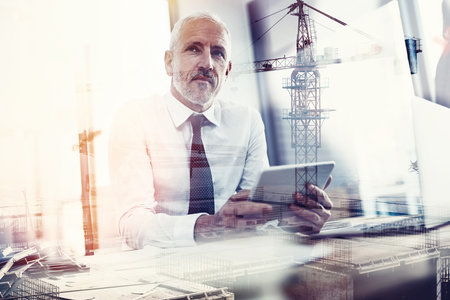 Building his own empire. a handsome mature businessman superimposed over a construction site.の写真素材