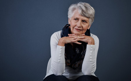 Take me back to the good old days. Studio shot of cheerful elderly woman sitting with her hands...
