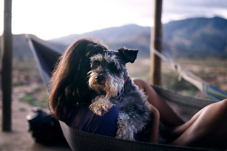 My human, my best friend. a young woman relaxing with her adorable dog in a hammock.の写真素材