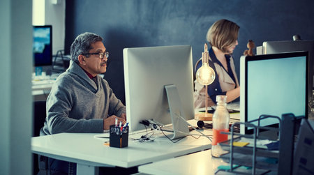 Committed to accomplishing their deadlines. two businesspeople working late in an office.