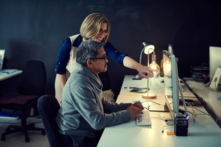 They truly put every minute of the day to good use. two businesspeople working late in an office.