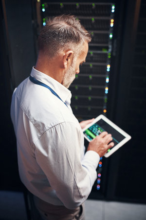 Smart technicians use smart apps. a mature man using a digital tablet while working in a server room.の写真素材