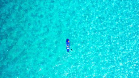 Just me against the blue. High angle shot of a man paddle boarding across the sea.