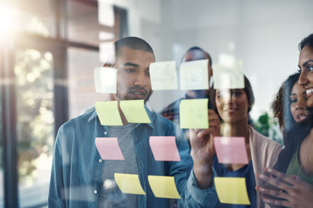 Working together to achieve success. a group of coworkers brainstorming on a glass wall.