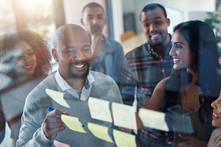 Youve gotta plan to succeed. High angle shot of a group of coworkers brainstorming on a glass wall.