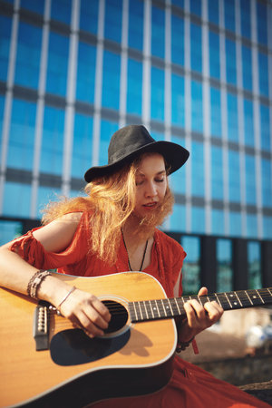 Music adds meaning to my life. a beautiful young woman out in the city with her guitar.の写真素材