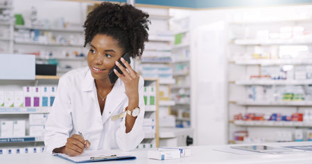 Time for some customer feedback. an attractive young pharmacist taking notes on a clipboard while on a phonecall.の写真素材