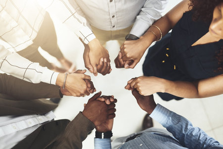 Their team is never short of supportive members. Closeup shot of a group of businesspeople holding...