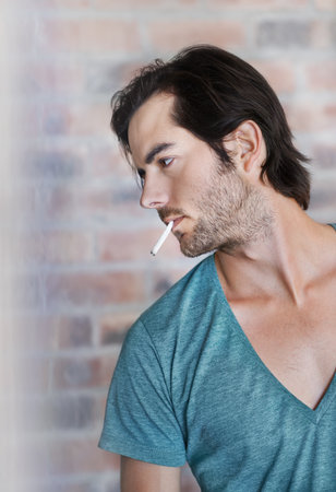 Smoking is part of his style. Close up profile of a handsome man with a cigarette in his mouth.の写真素材