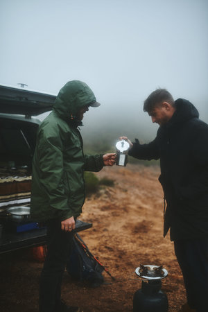 Coffee is the best way to warm up. two male friends having fresh coffee before hiking.