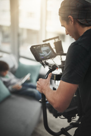 Just remain the way you are. Behind the scenes shot of a camera operator shooting a scene with a state of the art camera inside of a studio during the day.の写真素材