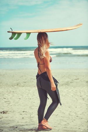 Let the waves guide your heart. a beautiful young woman going for a surf at the beach.の写真素材