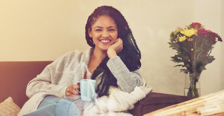 Embrace the boredom. a young woman enjoying a cup of coffee in her living room.の写真素材