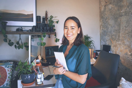 Thats me done for the day. an attractive young woman standing alone in her home office and holding...