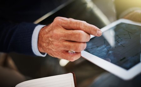 How the smart entrepreneur works. a businessman using a digital tablet at his work desk.の写真素材