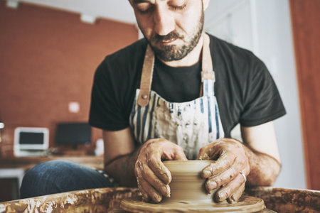 Creativity keeps the soul calm. a young man working with clay in a pottery studio.の写真素材