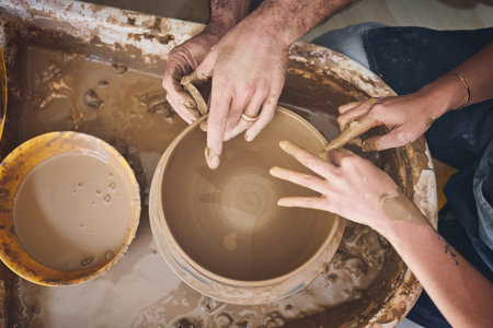 Lets get our hands dirty. an unrecognisable man and woman working with clay in a pottery studio.