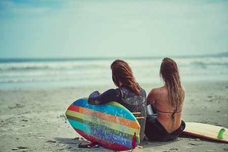 The waves are calling. a young couple surfing at the beach.の写真素材