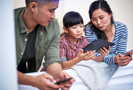 Connected in a contemporary world. a family using digital devices at home.の写真素材