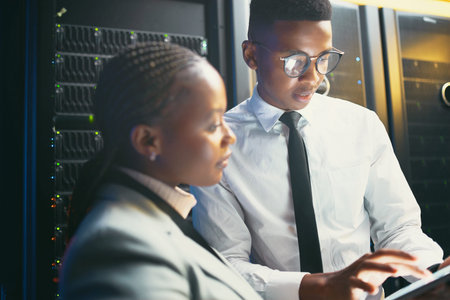 Lets work on this unit for now. two young IT specialists standing in the server room and having a...