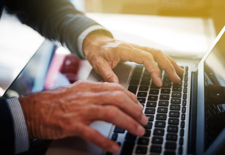 Connected to his work commitments. a businessman using a laptop at his work desk.